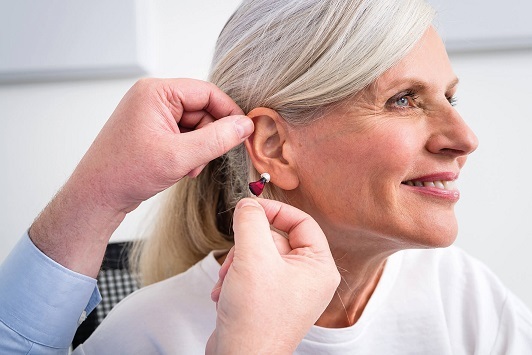 Eine ältere Frau bekommt ein modernes Hörgerät zur Hörverbesserung eingesetzt.